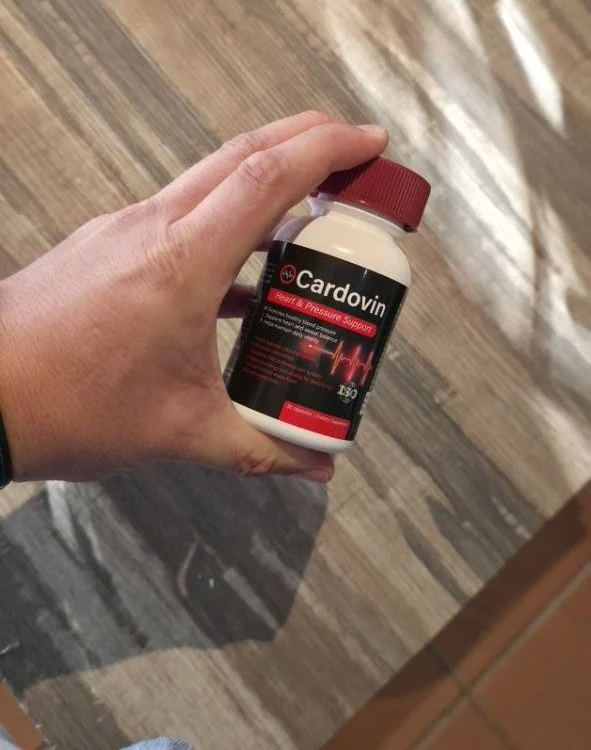 Hand holding the Cardovin bottle over a wooden desk